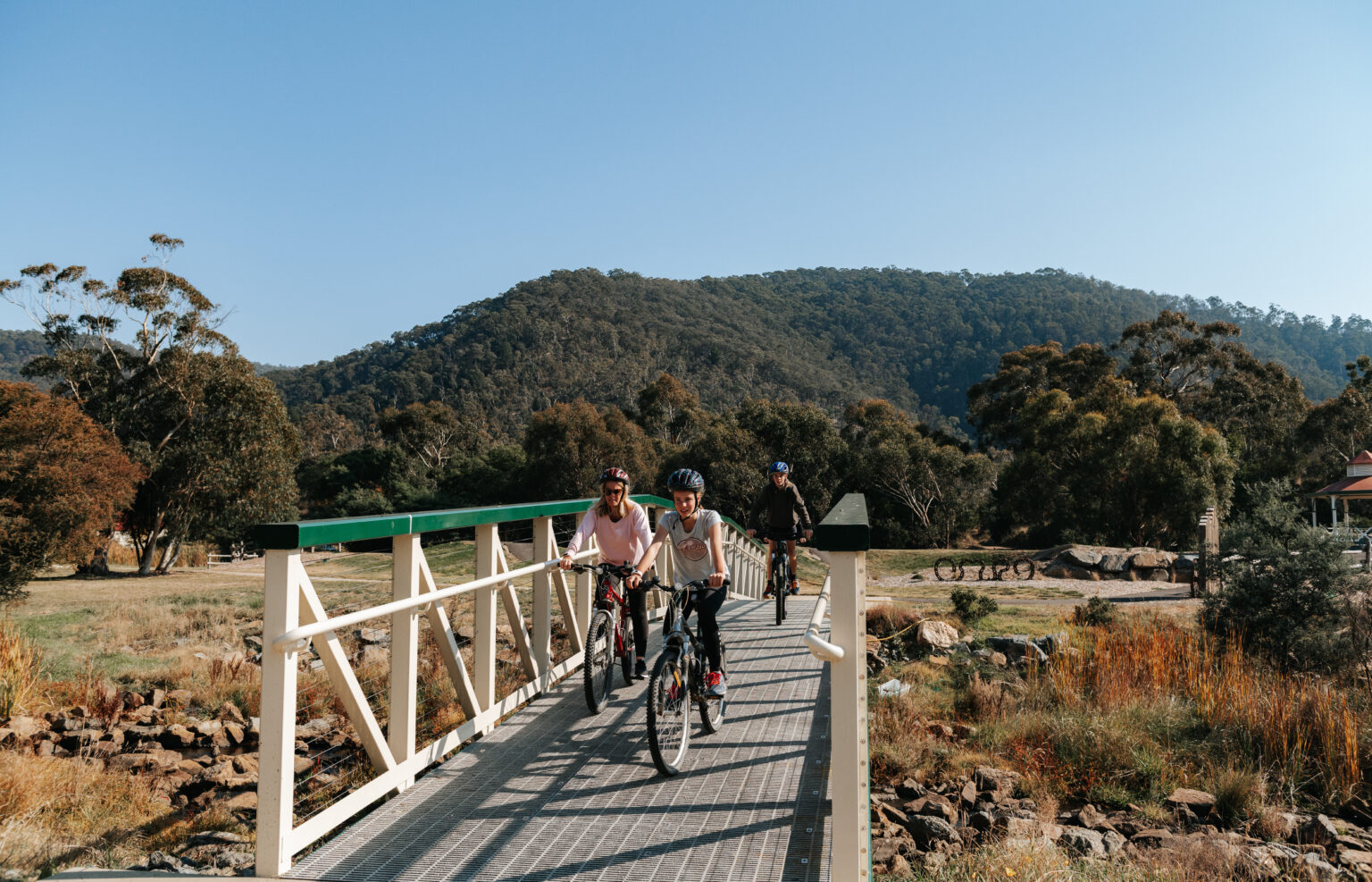Family cycling over bridge at Livingstone Park in Omeo