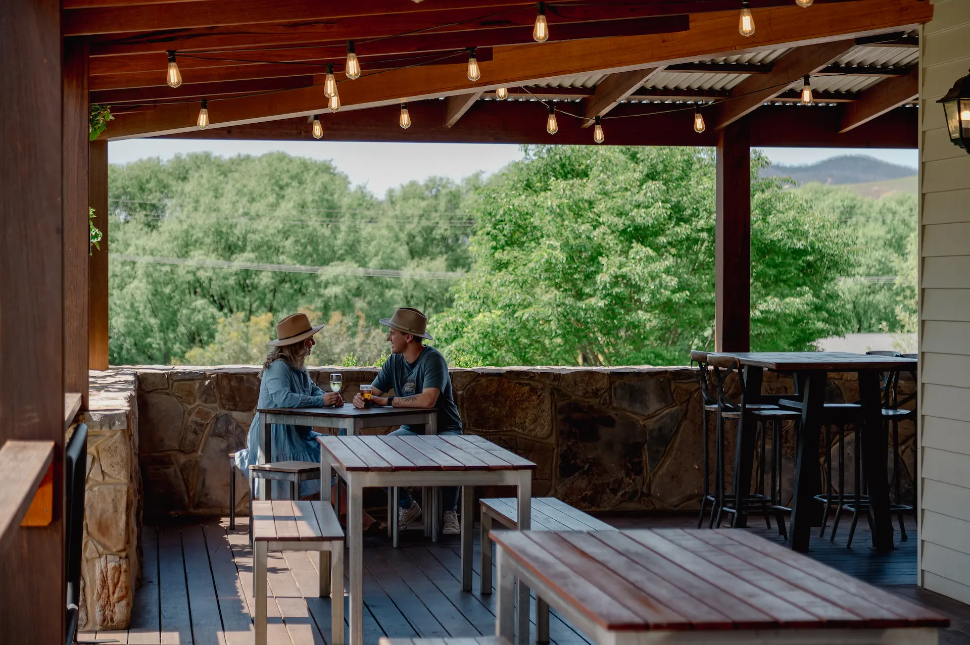 Couple enjoying drinks on the Buchan Hotel's outdoor deck overlooking bushland